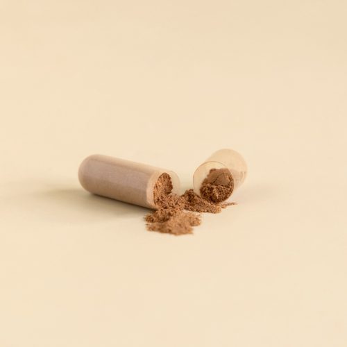 A supplement capsule has been split open to reveal the powder form of the supplement.